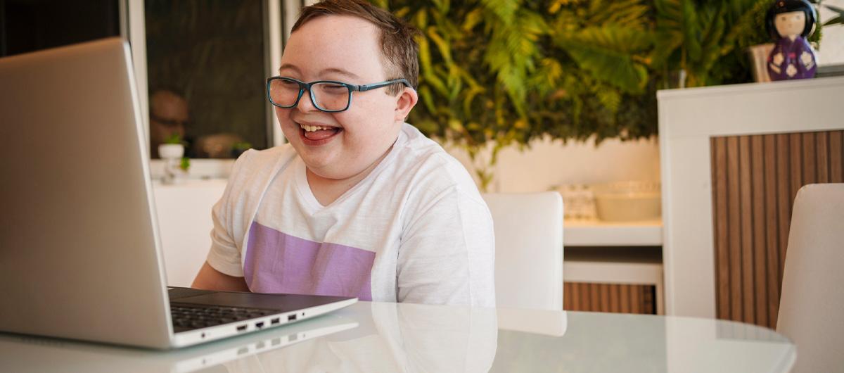 child with disability smiling on laptop