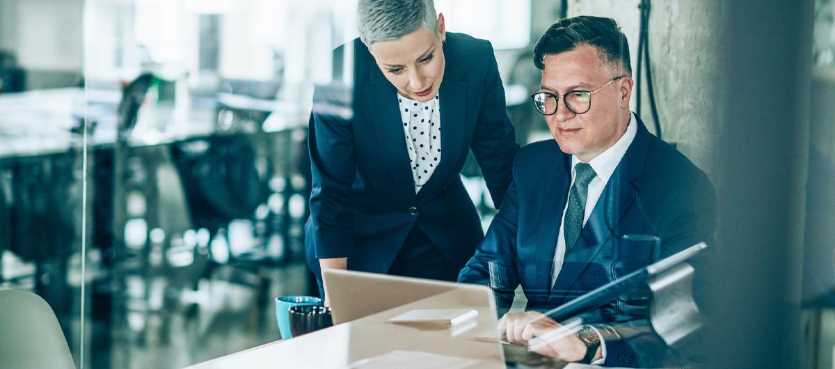 woman and woman in business attire on laptop