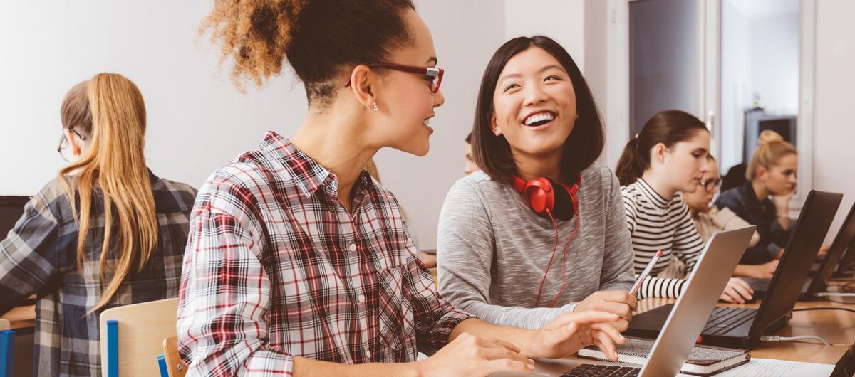 two woman talking with laptops