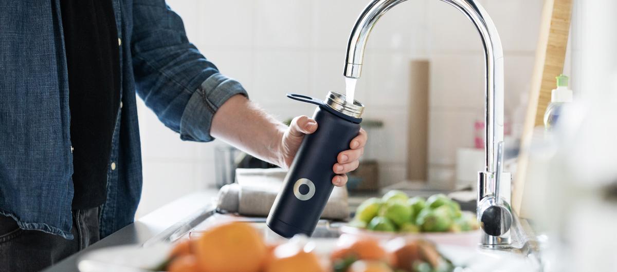 man using kitchen tap to fill water bottle