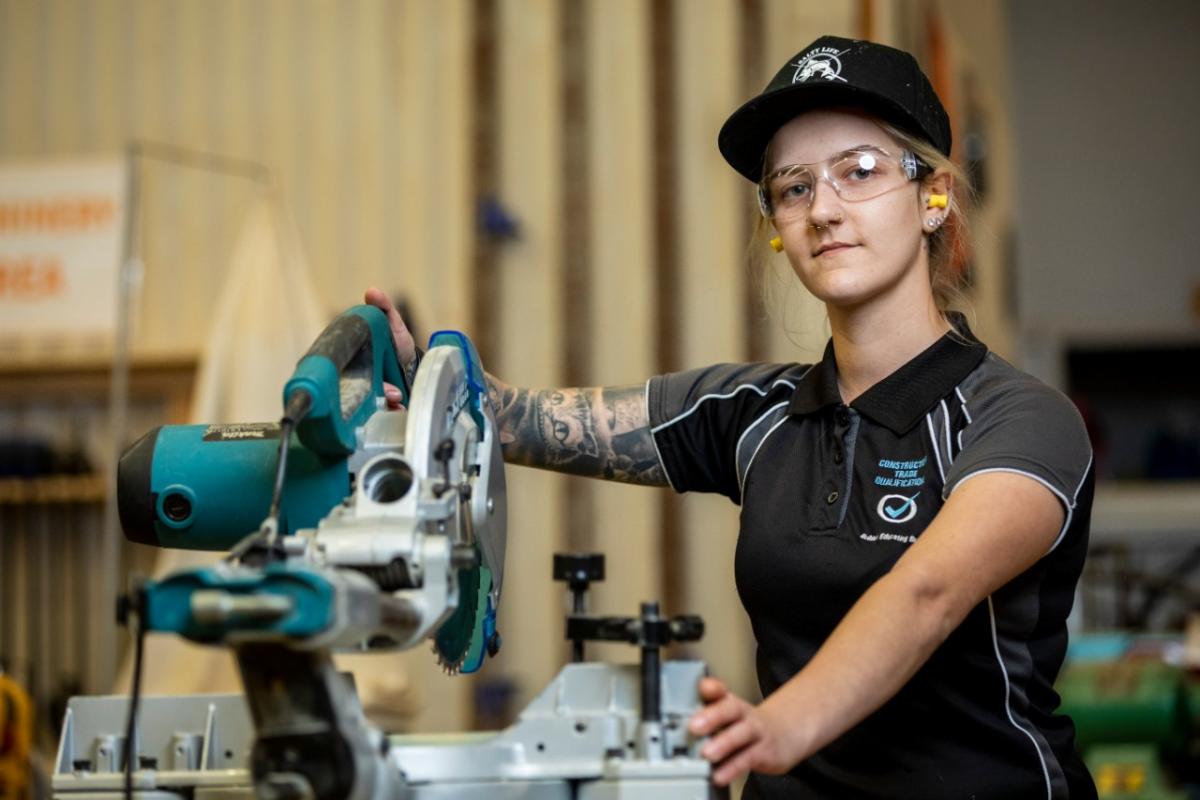 Female woodwork. Apprentice wearing safety equipment in a wood work shop 